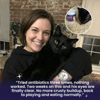 Woman testimonial holding a black cat with a product inset, brick wall background
